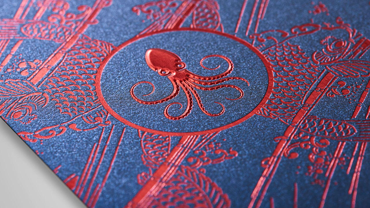 Dunkelblaue Fläche mit roten, metallischen 3D-Heißprägungen, Oktopus & Fische
