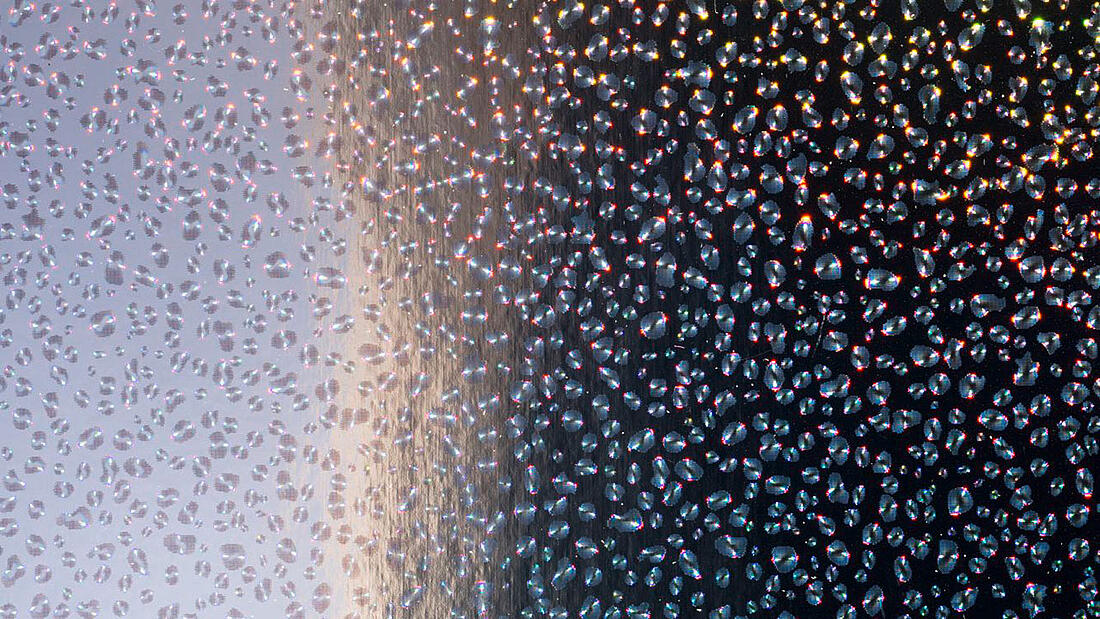 Diffraktive heißgeprägte Wassertropfen funkeln in Regenbogenfarben auf einem Hintergrund mit Farbverlauf