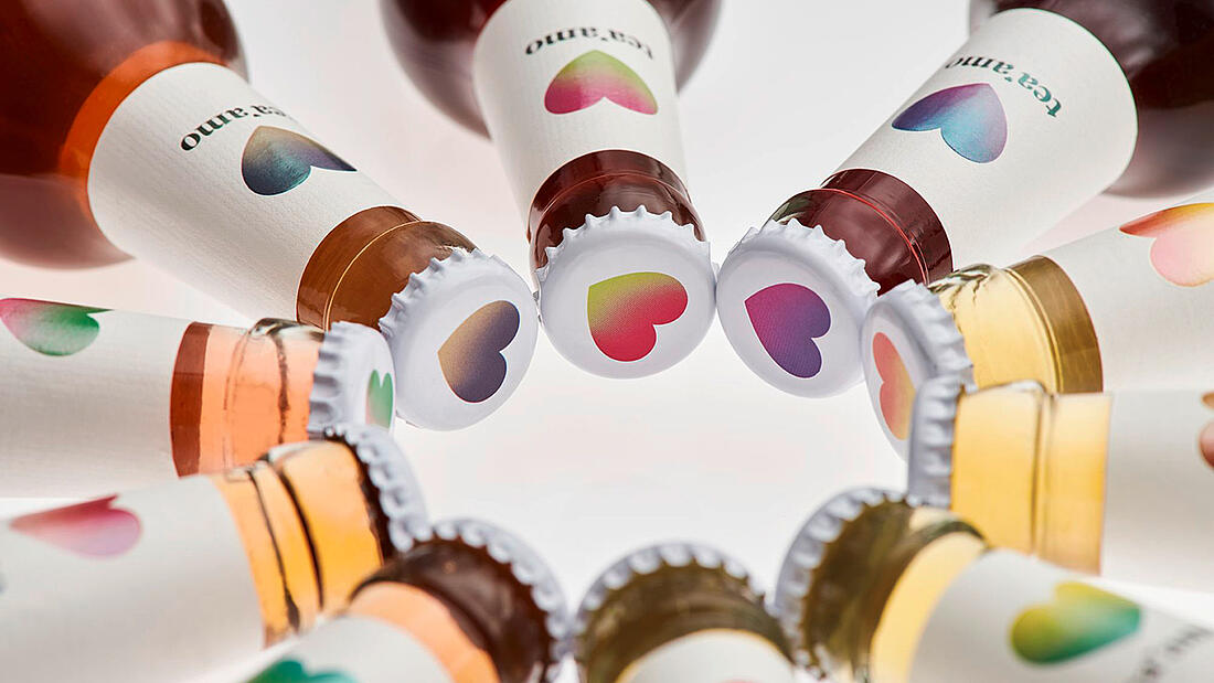 Ten glass bottles arranged in a circle, white labels and crown corks with hot-stamped heart design