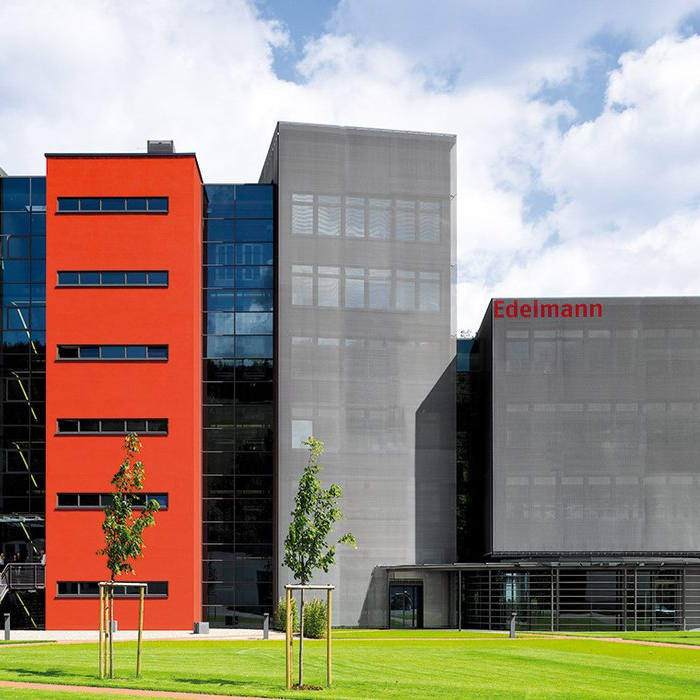 Photo of a multistory, contemporary company building with a red and dark gray facade