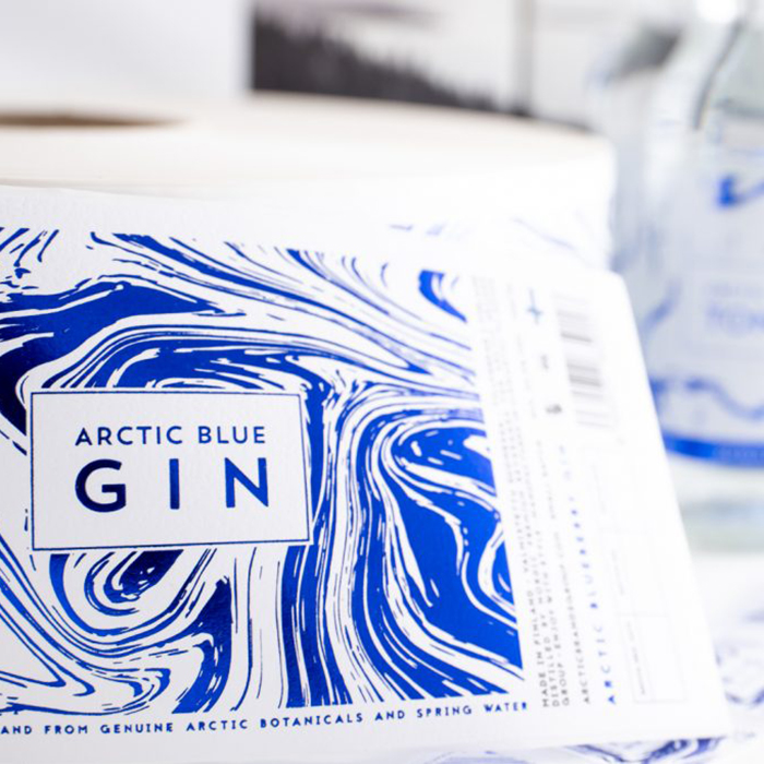 Foto von einem gedruckten Etikett für die Flasche des Arctic Blue Gin mit blau-weißem Design